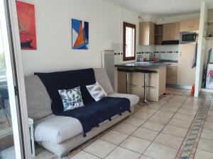a living room with a couch and a kitchen at Aigue Marine. in Canet-en-Roussillon