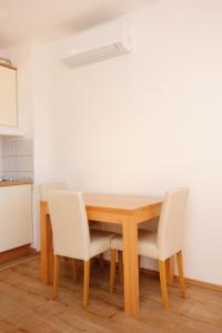 une table en bois avec des chaises blanches et une cuisine dans l'établissement Apartment Duce 9437e, à Dugi Rat