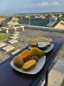 two plates of food sitting on a table with fruit at Villa verde Jamaica - Oceanview Getaway, Gated & Secured in Falmouth