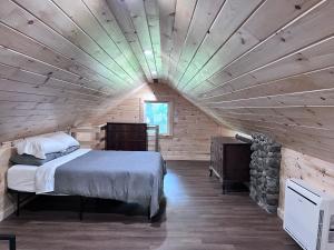- une chambre avec un grand lit dans une cabane en rondins dans l'établissement Camp Hudson Pines, à Corinth
