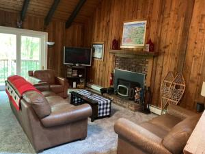 a living room with leather furniture and a fireplace at Dog friendly Chalet in the Woods w/Pool-Mt. Snow in Wilmington