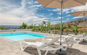 a pool with white chairs and an umbrella at Nice Home In La Isla De La Palma c With Outdoor Swimming Pool in Los Llanos de Aridane