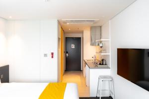 a bedroom with a white bed and a kitchen at Seogwipo Hills Hotel in Seogwipo
