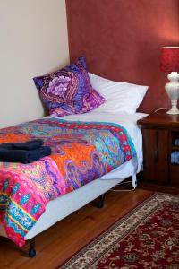 a bed with a colorful blanket and pillows on it at Gellibrand River Gallery Accommodation in Gellibrand