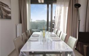 una larga mesa blanca con sillas blancas y una ventana en Residentie Crystal Ref 84, en Ostende