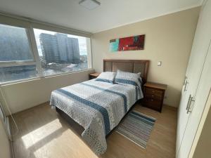 a bedroom with a bed and a large window at Departamento Chillan céntrico in Chillán