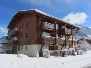 een groot houten gebouw met sneeuw op de grond bij Appartement Praz-sur-Arly, 1 pièce, 4 personnes - FR-1-603-63 in Praz-sur-Arly