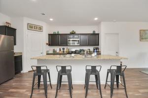 a kitchen with three bar stools and a counter at CHARMING 4 BEDROOMS BROOKSHIRE/KATY WITH GYM in Brookshire