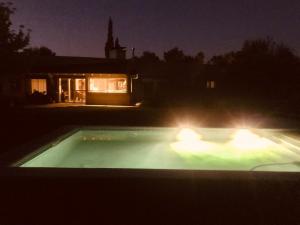 una piscina iluminada por la noche con luces en Los trinos en Coronel Suárez