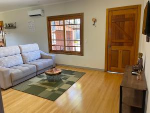 sala de estar con sofá, mesa y puerta en Casa Vita BG - Casa de campo en Bento Gonçalves