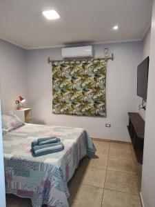 a bedroom with a bed with a painting on the wall at Casa con Garage Puerto Iguazú, zona residencial in Puerto Iguazú