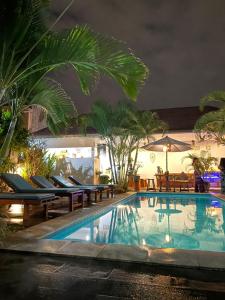 a swimming pool with lounge chairs and a resort at Canggu Nadi Guest House in Canggu