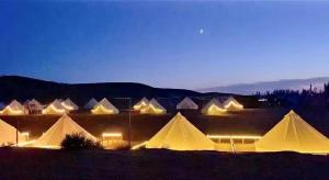 a group of white tents in a field at night at Dunhuang ManMan International Desert Outdoor Campground in Dunhuang