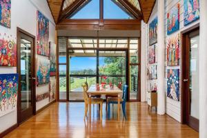 a dining room with a table and a large window at Donna's Art House in Alstonville