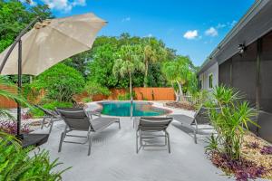 eine Terrasse mit Stühlen, einem Tisch und einem Sonnenschirm in der Unterkunft Your private tropical paradise with heated pool! in Sarasota