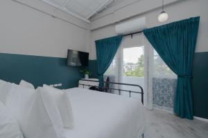 Un dormitorio con una cama blanca con paredes azules y una ventana en Blu Monkey Boutique Phuket Town, en Phuket