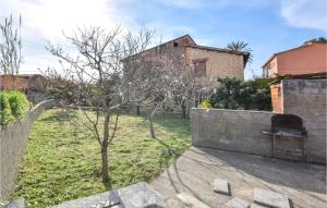 a brick wall with a tree in a yard at Stunning Home In Scaterina Di Pittinur in Santa Caterina +8 photos