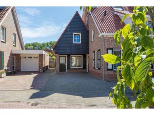 uma casa de tijolos com um telhado preto e uma entrada em Quietly located house within walking distance of the beach em Domburg