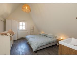 um quarto com uma cama com um urso de peluche ao lado de um lavatório em Quietly located house within walking distance of the beach em Domburg