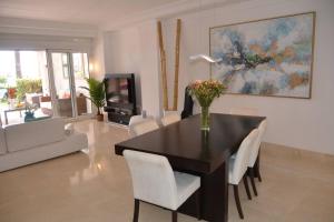 uma sala de estar com uma mesa de jantar com cadeiras brancas em Lovely 2 bedroom unit with private pool em Sotogrande