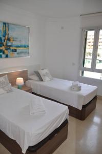 Duas camas num quarto branco com uma janela em Lovely 2 bedroom unit with private pool em Sotogrande