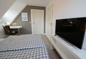 Schlafzimmer mit einem Bett und einem Flachbild-TV in der Unterkunft Haus Katharina links in Wyk auf Föhr