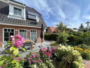 ein Haus mit einem Zaun und Blumen im Hof in der Unterkunft Haus Katharina links in Wyk auf Föhr