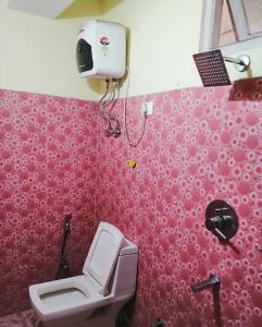 a bathroom with a toilet and a pink wall at Hotel Nindik in Gangtok