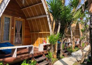 a wooden cabin with a porch with trees and plants at Paradesa Villa in Gili Trawangan