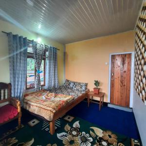een slaapkamer met een bed en een raam bij The Swarna Homestay in Darjeeling