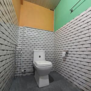 een badkamer met een wit toilet in een bakstenen muur bij The Swarna Homestay in Darjeeling
