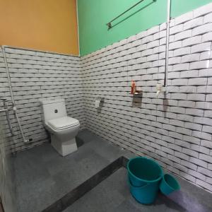 een badkamer met een toilet en een witte bakstenen muur bij The Swarna Homestay in Darjeeling