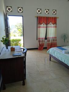 a bedroom with a bed and a desk and a window at ANDY'S LODGE KELIMUTU in Kelimutu