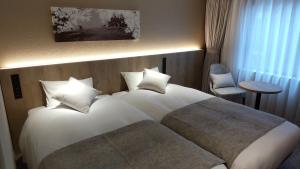 a hotel room with two beds and a chair at Iroha Grand Hotel Kintetsu Nara Ekimae in Nara