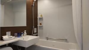 a bathroom with a sink and a tub and a mirror at Iroha Grand Hotel Kintetsu Nara Ekimae in Nara