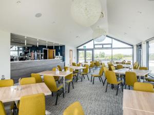 a dining room with tables and yellow chairs at Number 8 Lakes View in Burnham on Sea