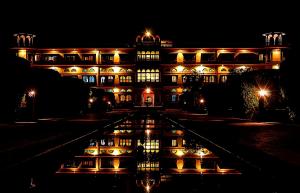 un edificio iluminado por la noche con un reflejo en el agua en Umaid Palace - Luxury Resort Near Jaipur Close to Bhangarh & Chand Baori Stepwell Abhaneri, en Dubbī