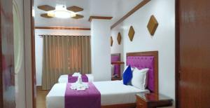 a bedroom with two beds with purple and white sheets at CLN Boutique Hotel in Tacloban