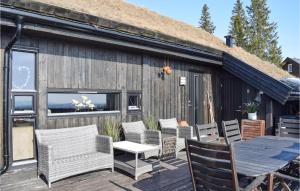 a deck with chairs and a table and a building at Cozy Home In Sjusjen With Sauna in Sjusjøen