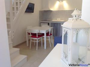a kitchen and dining room with a white table and chairs at Victoria House Scopello in Scopello