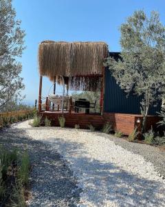 a building with a straw roof on a gravel road at Lovin Gocek & Tiny house Mermaid in Fethiye