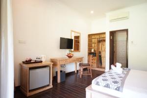 a bedroom with a bed and a desk and a television at Royal Regantris Villa Karang in Gili Air