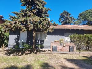 una casa con un árbol delante en El Cazón Home, en Pinamar