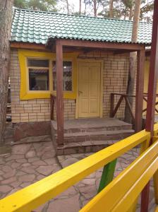 a small house with a yellow door and a porch at Гостевой дом Azia in Borovoye