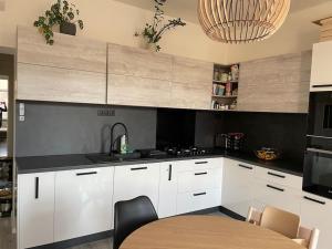 a kitchen with white cabinets and a sink and a table at Lovely 2-bedroom apartment in centre of Bratislava in Bratislava