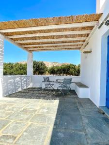 a patio with two chairs and a wooden pergola at A Cycladic-architecture Beach House in Koumbara in Tzamaria