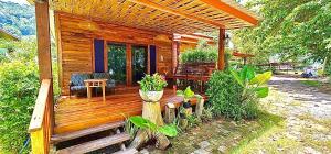a wooden cabin with a deck with a table and chairs at Coconut Lanta Resort @Klong Dow beach in Krabi town