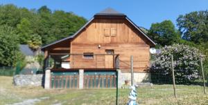 une grange en bois avec un portail dans un champ dans l'établissement Chalet au cœur du Val d'Azun, à Arras-en-Lavedan