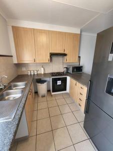 a kitchen with wooden cabinets and a stainless steel refrigerator at Elegant 2 bed apartment next to Gautrain Centurion in Centurion