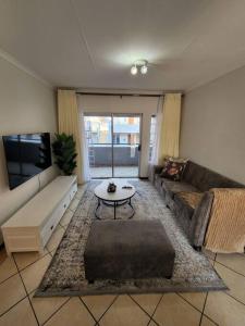 a living room with a couch and a tv at Elegant 2 bed apartment next to Gautrain Centurion in Centurion